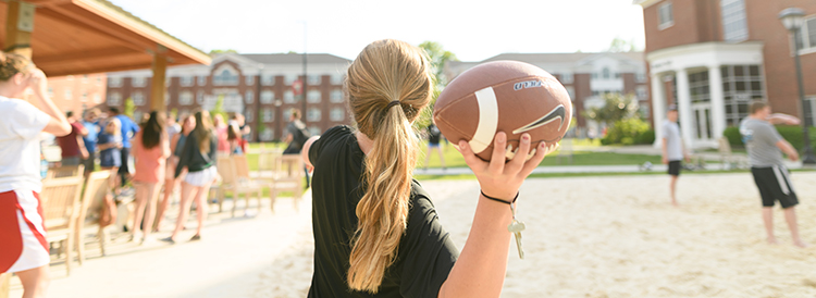 on campus recreation, student throwing football