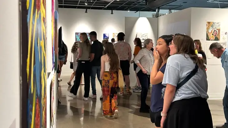 people walking through an art gallery looking at artwork on the wall