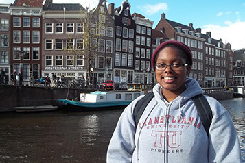 student standing in front of buildings along a canal