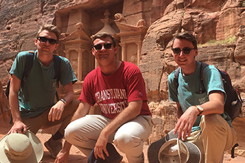 students in front of a structure built into a stone wall