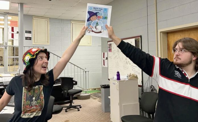 two transy students holding up comic book