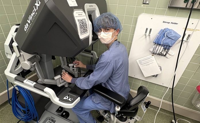 person in medical scrubs sitting at high-tech medical device