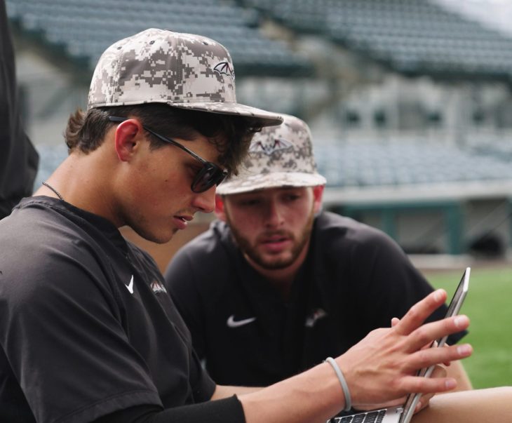 two baseball player looking at a laptop